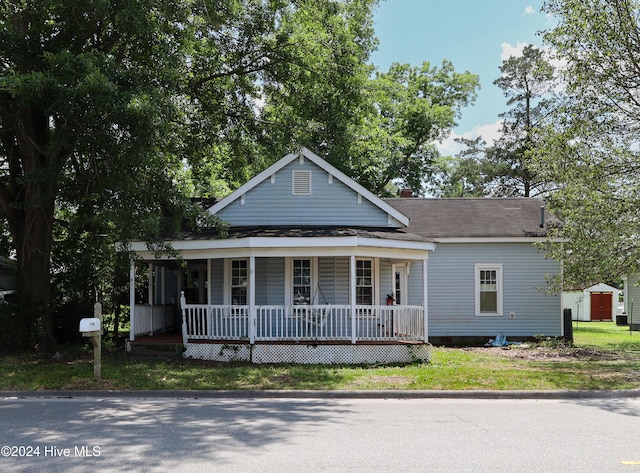 view of front of property featuring a porch and a storage shed