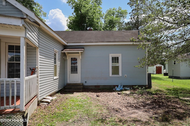 rear view of house featuring a yard and a storage shed