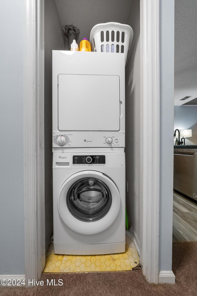 laundry area with tile patterned flooring, stacked washer / dryer, and a textured ceiling