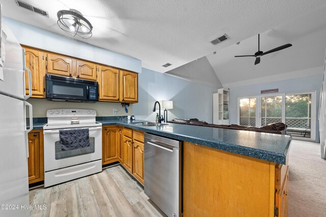 kitchen featuring kitchen peninsula, light colored carpet, a textured ceiling, white appliances, and a kitchen bar