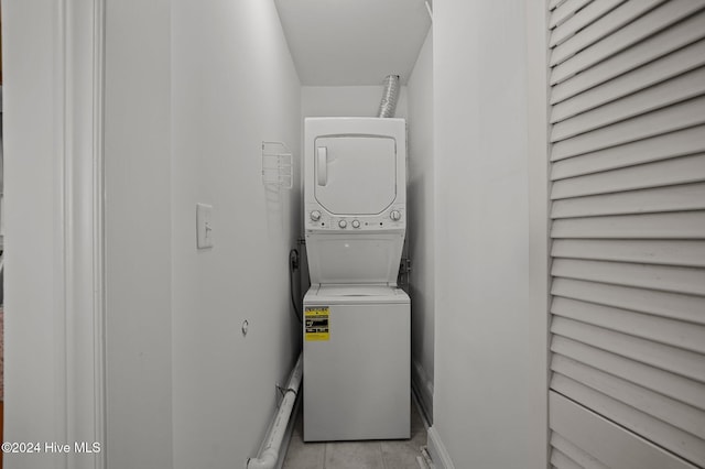 laundry area with stacked washer and clothes dryer and light tile patterned floors