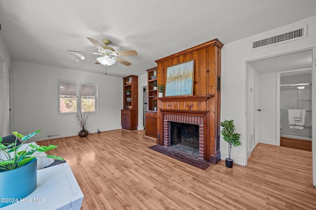 living room featuring ceiling fan, light hardwood / wood-style floors, and a brick fireplace