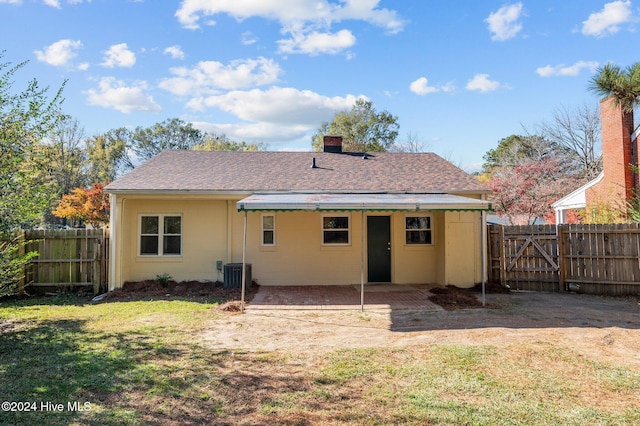 back of property featuring central AC unit, a patio area, and a lawn