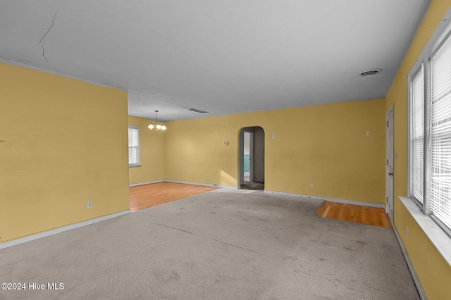 carpeted spare room with a chandelier