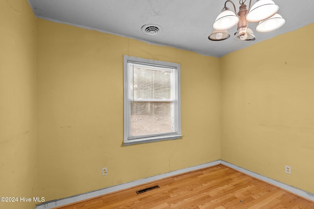 unfurnished room with a chandelier and hardwood / wood-style flooring