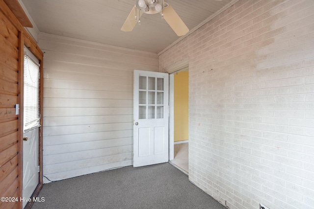 carpeted empty room with ceiling fan and wooden walls