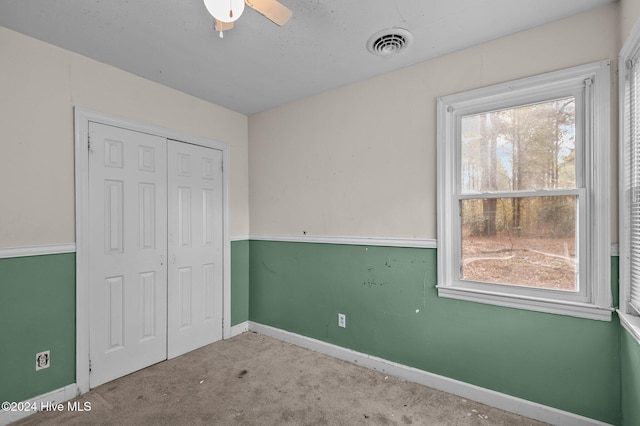 unfurnished bedroom featuring multiple windows, ceiling fan, a closet, and light colored carpet