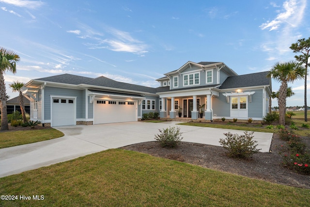 view of front of house with covered porch, a front yard, and a garage