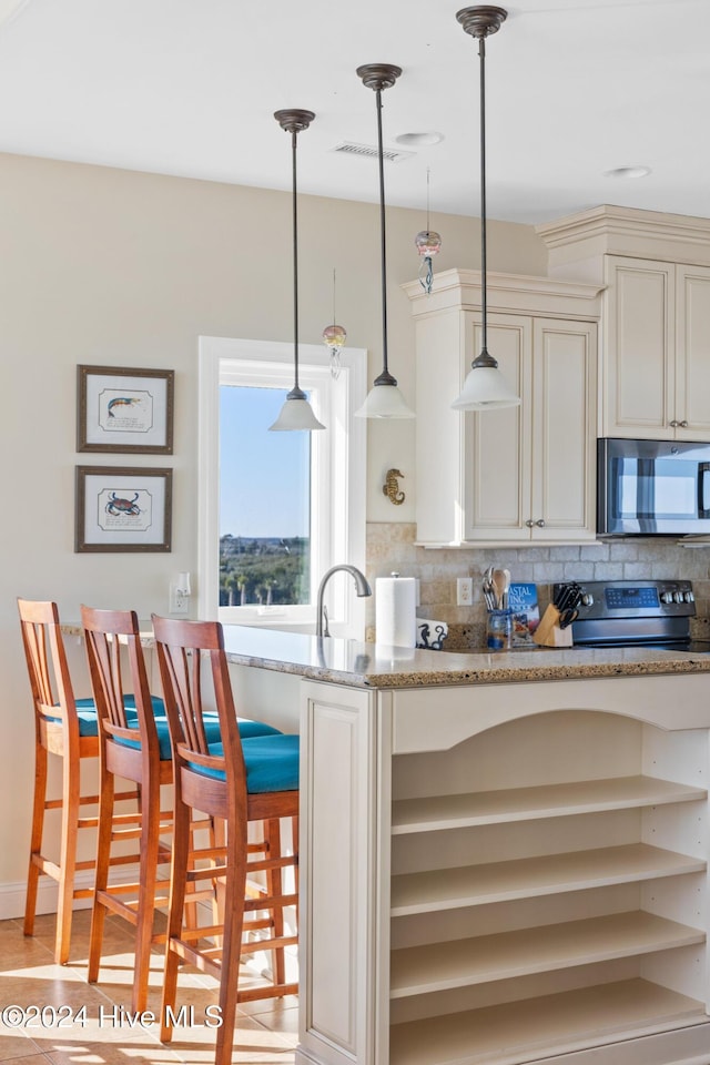 kitchen featuring tasteful backsplash, stainless steel appliances, light stone countertops, and hanging light fixtures