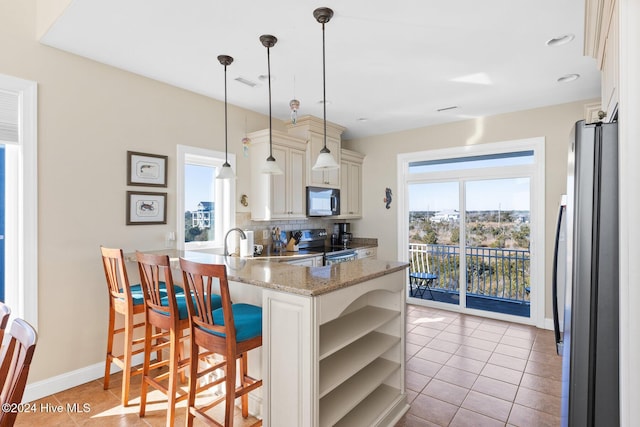 kitchen featuring decorative light fixtures, refrigerator, kitchen peninsula, electric stove, and decorative backsplash