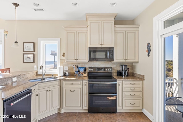 kitchen with pendant lighting, sink, cream cabinetry, and appliances with stainless steel finishes