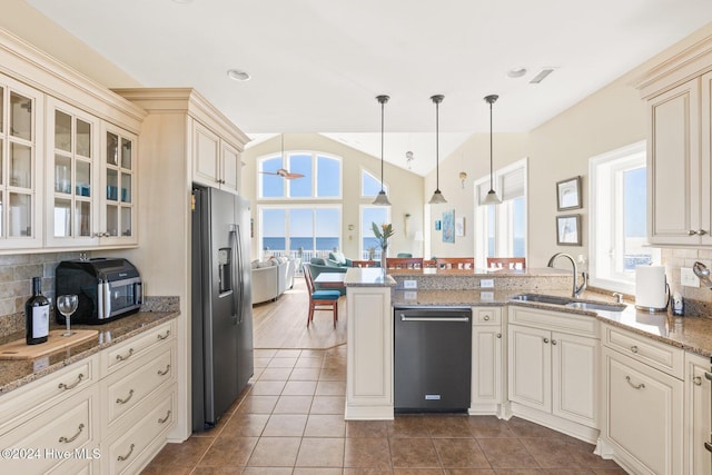 kitchen with stone counters, pendant lighting, sink, stainless steel fridge with ice dispenser, and cream cabinetry