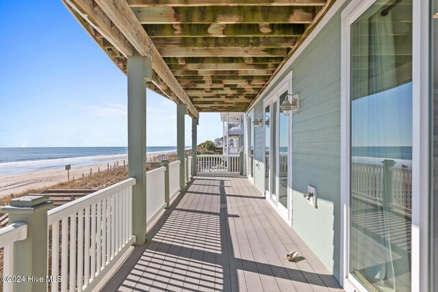 balcony featuring a view of the beach and a water view