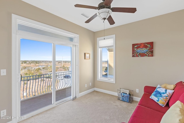 living area featuring plenty of natural light, light colored carpet, and ceiling fan