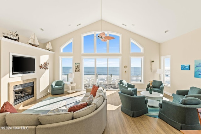 living room featuring a water view, light wood-type flooring, a fireplace, and plenty of natural light