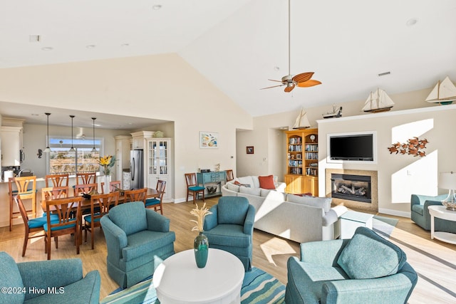 living room featuring ceiling fan, high vaulted ceiling, and light wood-type flooring