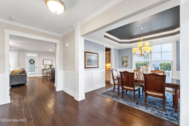 dining area featuring a chandelier, dark hardwood / wood-style flooring, a raised ceiling, and ornamental molding