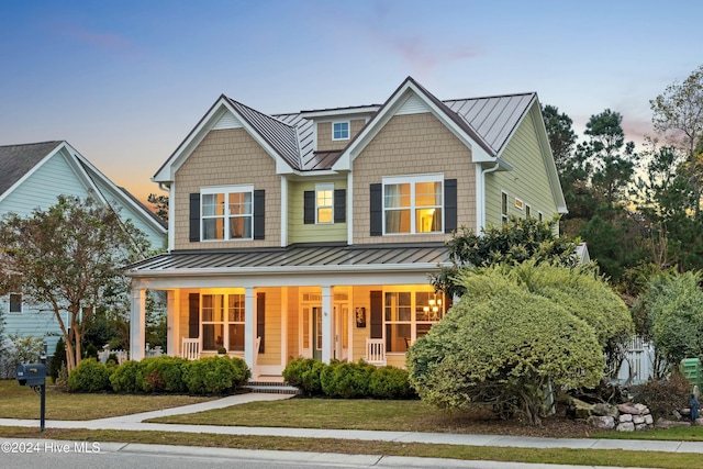 view of front of house with covered porch and a yard