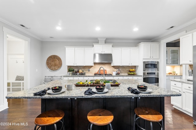 kitchen featuring light stone countertops, stainless steel appliances, and an island with sink