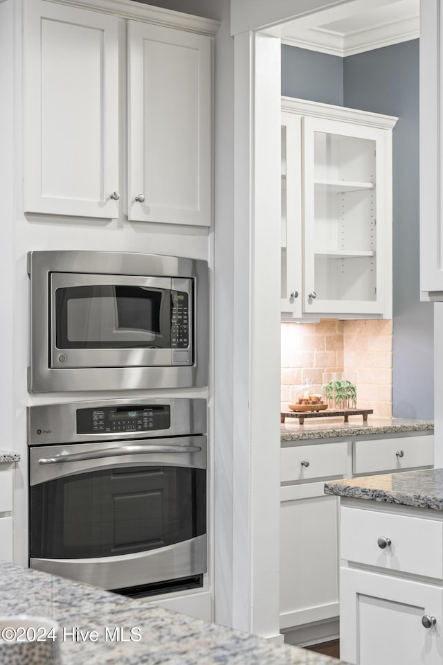 kitchen featuring light stone countertops, appliances with stainless steel finishes, and white cabinetry