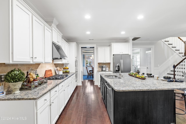 kitchen featuring dark hardwood / wood-style flooring, an island with sink, decorative backsplash, white cabinets, and appliances with stainless steel finishes