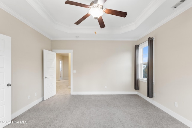 unfurnished room featuring light colored carpet, ornamental molding, and a tray ceiling