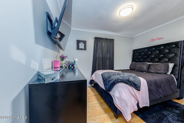 bedroom with a textured ceiling, light hardwood / wood-style flooring, and ornamental molding