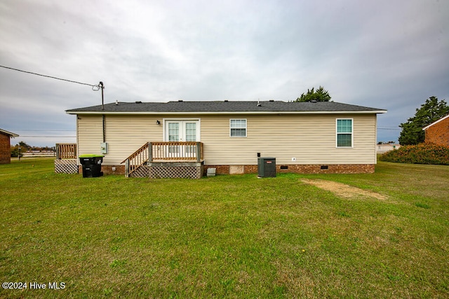 rear view of house featuring central AC and a lawn