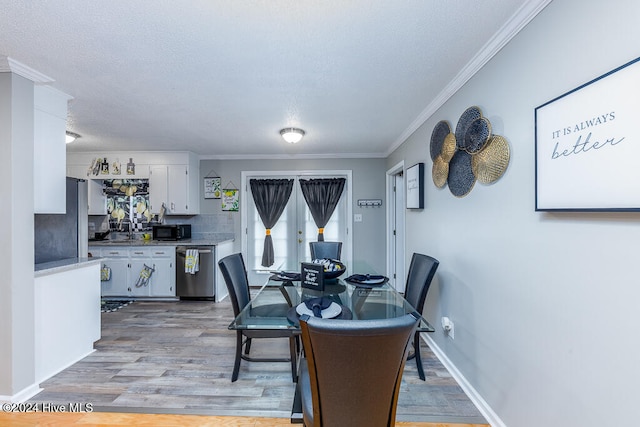 dining area featuring a textured ceiling, light wood-type flooring, and crown molding