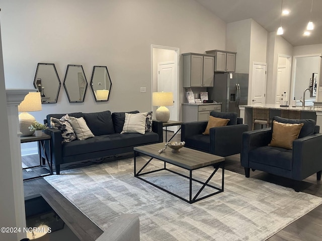 living room featuring sink, high vaulted ceiling, and light hardwood / wood-style flooring