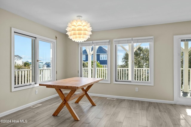 unfurnished dining area with a notable chandelier, plenty of natural light, and light hardwood / wood-style floors