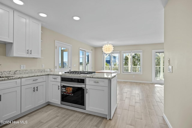 kitchen with kitchen peninsula, white cabinetry, stainless steel appliances, and light wood-type flooring