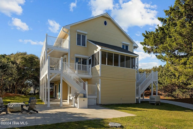 rear view of house with a sunroom, cooling unit, a patio, and a lawn