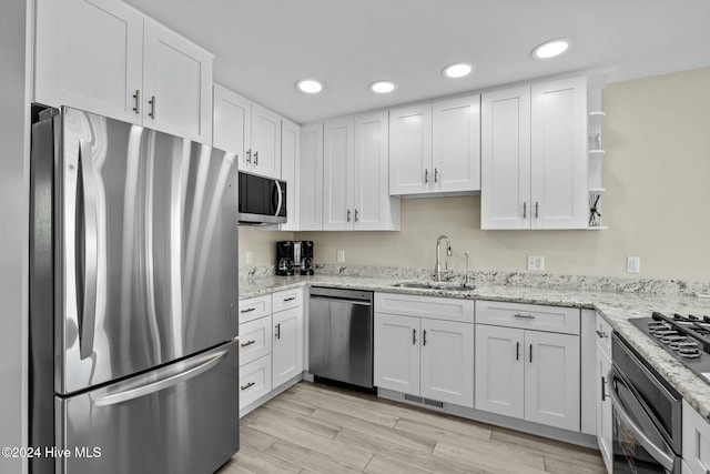 kitchen with light wood-type flooring, stainless steel appliances, white cabinetry, and sink