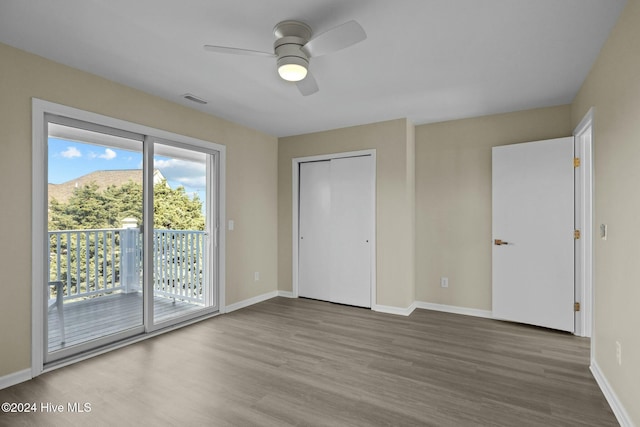 unfurnished bedroom featuring access to exterior, ceiling fan, a mountain view, wood-type flooring, and a closet