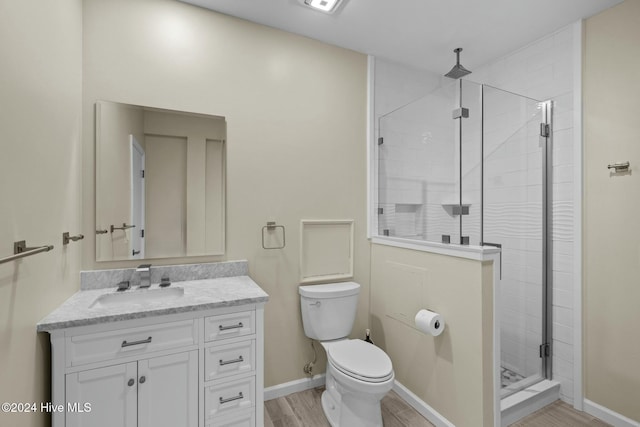 bathroom featuring vanity, hardwood / wood-style flooring, toilet, and a shower with shower door