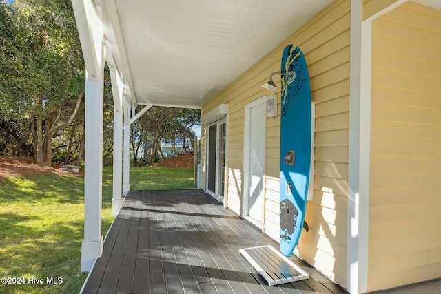 wooden deck featuring covered porch and a yard