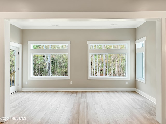 spare room featuring crown molding and light wood-type flooring