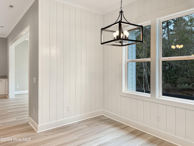 unfurnished dining area with light hardwood / wood-style flooring, a chandelier, and ornamental molding