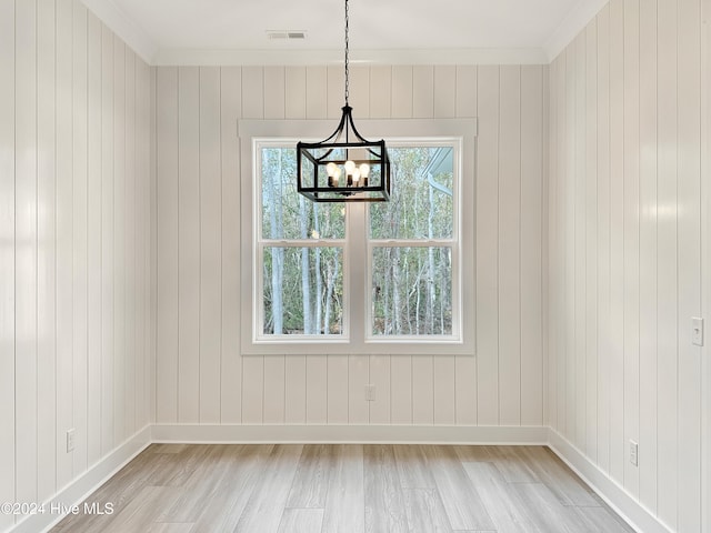 unfurnished dining area with wood walls, light hardwood / wood-style floors, and ornamental molding