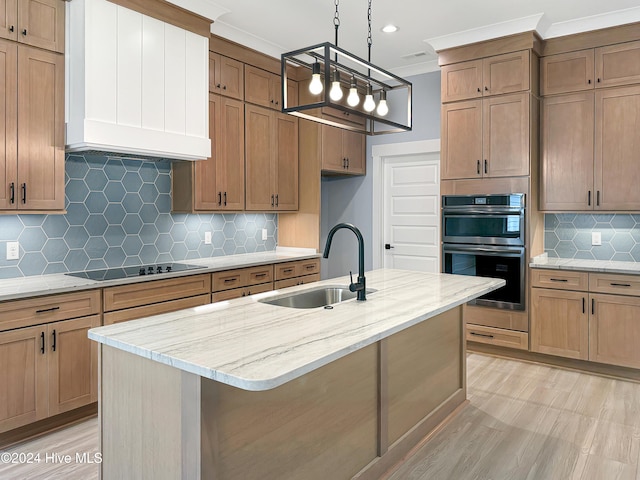 kitchen featuring premium range hood, tasteful backsplash, sink, and an island with sink