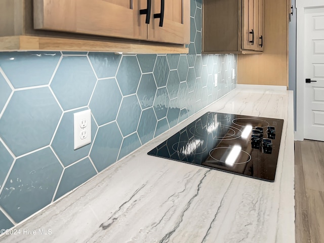 kitchen featuring decorative backsplash, black electric cooktop, and hardwood / wood-style flooring