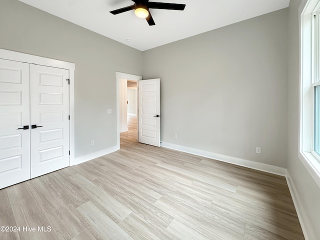 unfurnished bedroom with ceiling fan, light wood-type flooring, and a closet