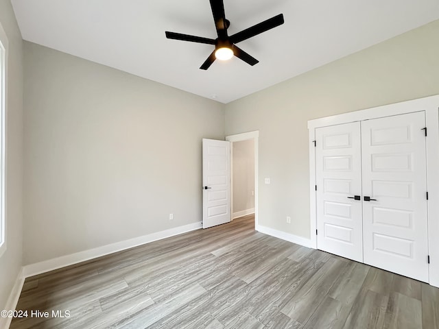 unfurnished bedroom with ceiling fan, a closet, and light hardwood / wood-style flooring