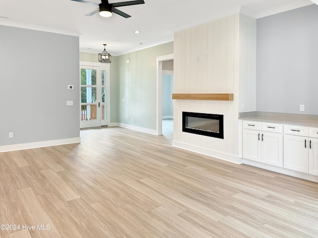 unfurnished living room featuring ceiling fan with notable chandelier, crown molding, a fireplace, and light hardwood / wood-style flooring