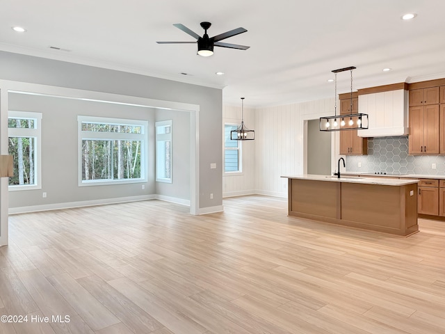 kitchen with decorative light fixtures, a kitchen island with sink, and light hardwood / wood-style flooring