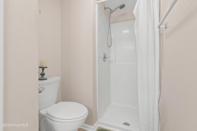 bathroom featuring a shower with shower curtain and toilet