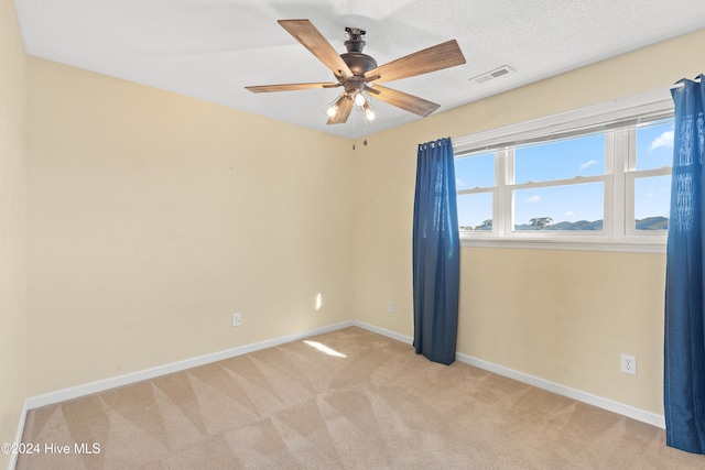 carpeted spare room featuring ceiling fan and a textured ceiling