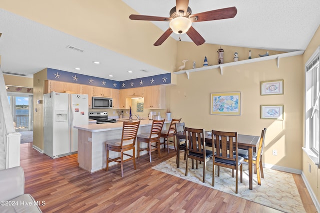 dining area with wood-type flooring, a textured ceiling, high vaulted ceiling, and ceiling fan