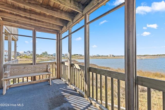 unfurnished sunroom with beamed ceiling, a water view, and wooden ceiling